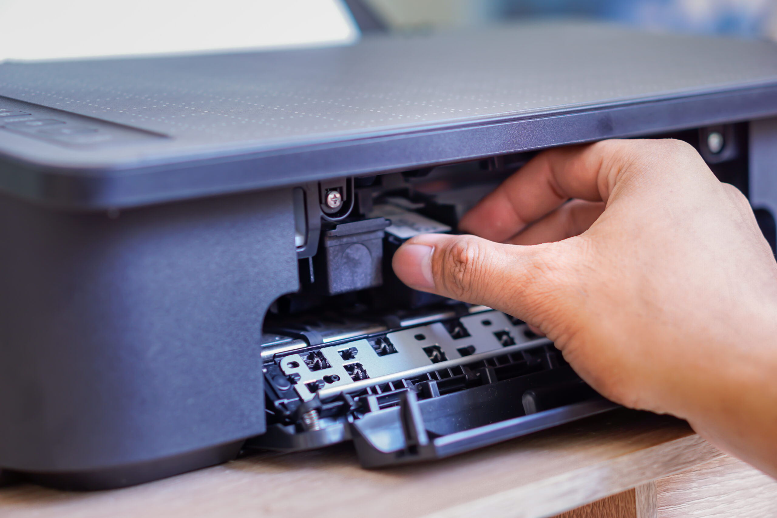 a person is installing a black ink cartridge into a printer.